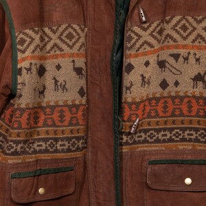 May include: A brown leather jacket with a zipper closure and a patterned fabric lining. The lining features a geometric design with animal figures and a brown, orange, and beige color scheme.