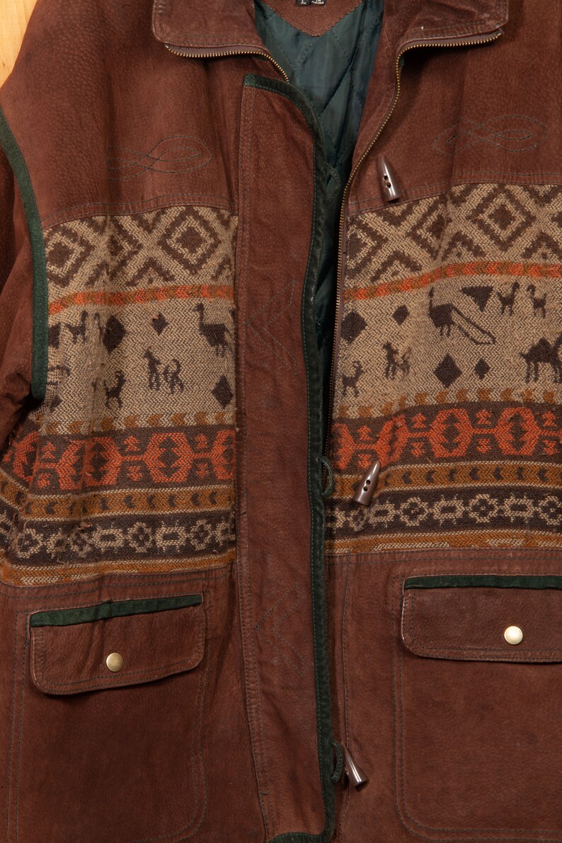 May include: A brown leather jacket with a zipper closure and a patterned fabric lining. The lining features a geometric design with animal figures and a brown, orange, and beige color scheme.