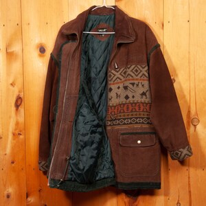 May include: A brown suede jacket with a patterned fleece lining. The jacket has a zipper closure, two pockets, and a toggle closure at the neck.