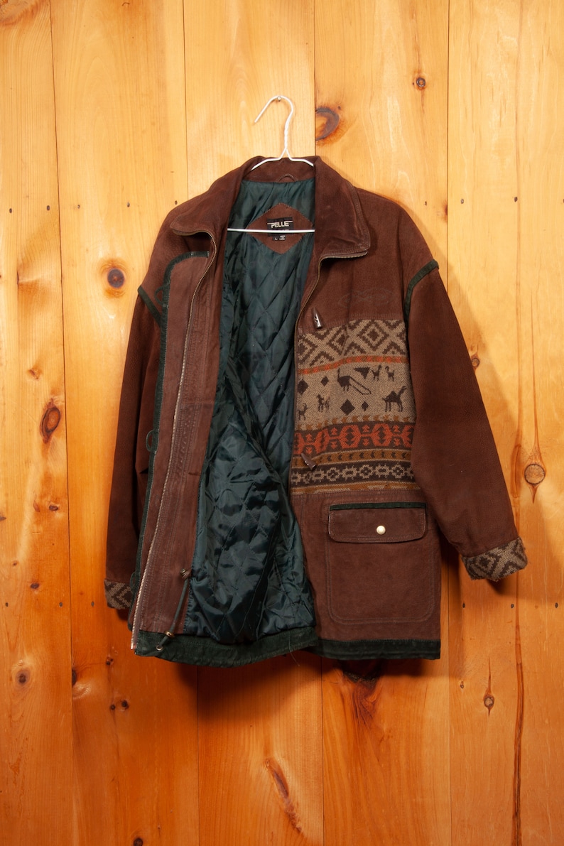 May include: A brown suede jacket with a patterned fleece lining. The jacket has a zipper closure, two pockets, and a toggle closure at the neck.