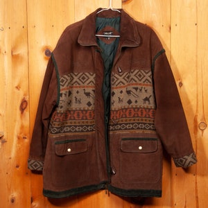 May include: A brown suede jacket with a geometric patterned lining. The jacket has two large pockets and a zipper closure. The label on the jacket reads "Pelle".