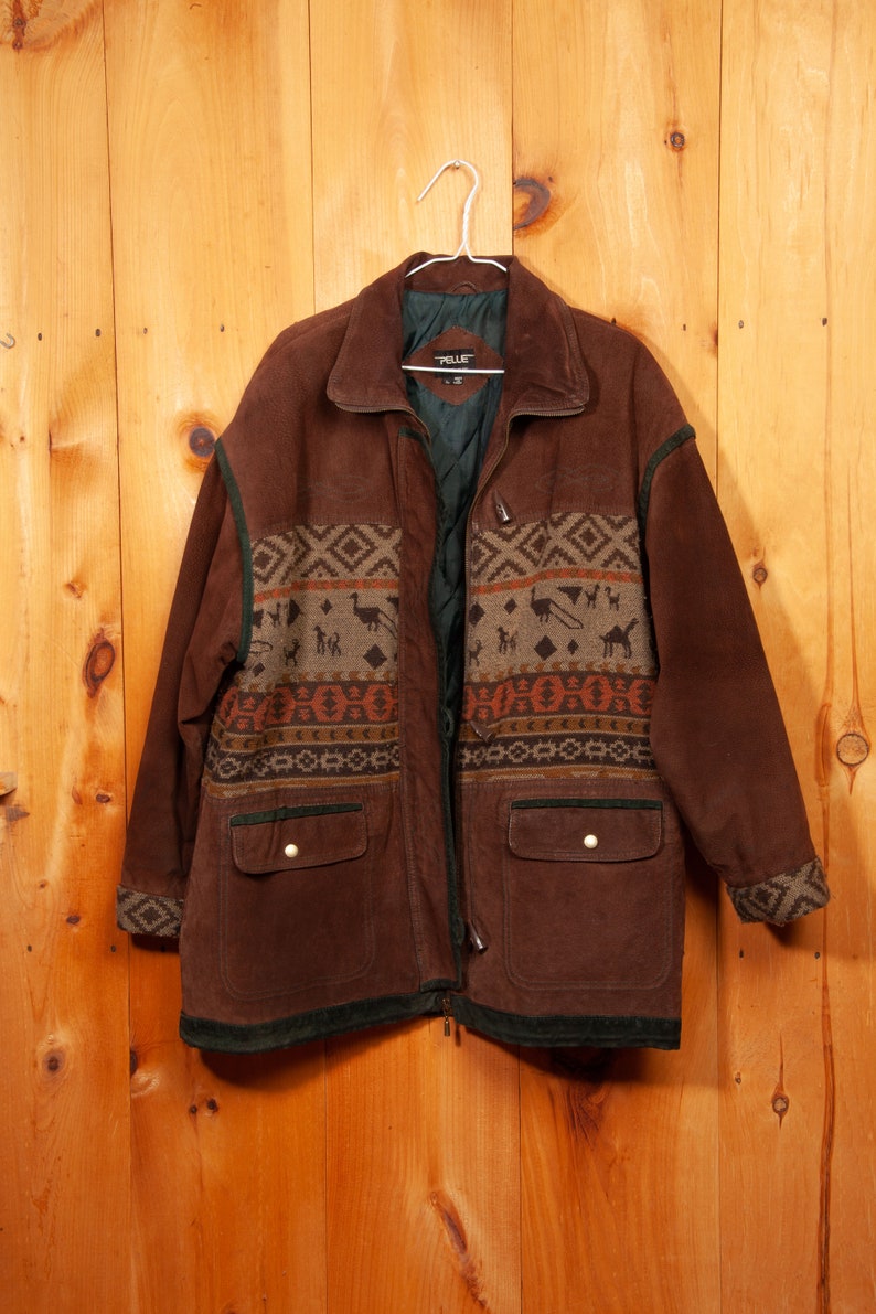 May include: A brown suede jacket with a geometric patterned lining. The jacket has two large pockets and a zipper closure. The label on the jacket reads "Pelle".