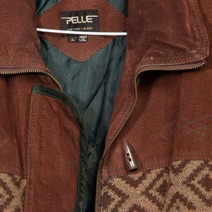 May include: A brown suede jacket with a zipper closure and a patterned fabric lining. The jacket has a label that reads "PELLE NEW YORK - MELAND" and "MADE IN CHINA".