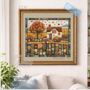 Puede incluir: Una obra de arte en punto de cruz enmarcada representa una casa pintoresca con un tejado rojo, rodeada de un jardín colorido y un gran árbol con follaje otoñal. La obra está en un marco dorado y presenta el texto "Mariska Art".