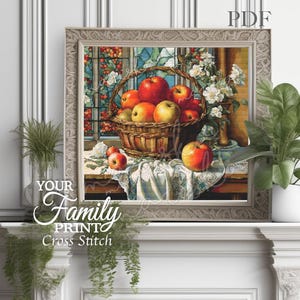 Puede incluir: Un patrón de punto de cruz que presenta una cesta llena de manzanas rojas y verdes. La cesta está sobre un mantel blanco con encaje. El fondo es una pintura de una ventana con vidrieras y un jarrón de flores.