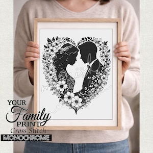 May include: A framed monochrome cross-stitch artwork. It depicts a bride and groom silhouette inside a floral heart, set in a wooden frame. The text at the bottom reads "YOUR Family PRINT Cross Stitch MONOCHROME".