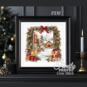 Può includere: Un disegno a punto croce incorniciato raffigurante una scena invernale con una casa, regali e un arco festivo. L'opera presenta un fiocco rosso, candele e il testo "YOUR Family PRINT Cross Stitch".