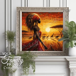 Può includere: Opera d'arte a punto croce incorniciata raffigurante una donna africana in abito rosso, ornata di gioielli e copricapo, ambientata in un paesaggio al tramonto con giraffe e altra fauna selvatica. L'opera è in una cornice decorativa. Il testo in basso a sinistra dice "YOUR Family PRINT Cross Stitch."
