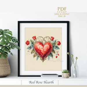 Op de afbeelding: Borduurpatroon met een rood hart met sierlijke gouden krulwerk en rode rozen. Het patroon is getiteld "Red Rose Hearth" en is voor een 9,37 x 12,5 inch Aida-stof met 16 draden. Het patroon gebruikt DMC 20 garen.