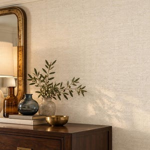 May include: A textured off-white wallpaper with a subtle woven fabric pattern. The surface features a fine, cross-hatched grid design that mimics the appearance of linen, providing a neutral and consistent backdrop with a soft, matte finish.