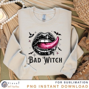May include: A beige sweatshirt with a black and pink graphic of a mouth with a tongue sticking out. The graphic is surrounded by stars and bats. The text "Bad Witch" is printed below the graphic.