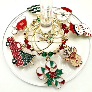 May include: Set of eight gold-tone Christmas-themed wine glass charms. The charms feature a snowman, a reindeer, a candy cane, a Christmas tree, a Santa hat, a mitten, a truck, and a Santa hat.