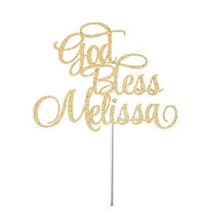 May include: Gold glitter cake topper with the text "God Bless Melissa" in a cursive font.