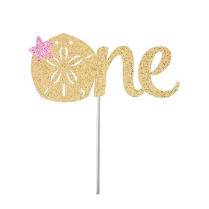 May include: Gold glitter cake topper with the word "one" and a pink glitter starfish on a seashell.