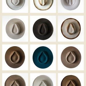 Puede incluir: Una colección de doce sombreros fedora en varios colores, incluyendo gris, marrón y verde azulado. Cada sombrero presenta una corona en forma de lágrima y un ala ancha. Los sombreros están dispuestos en un patrón de cuadrícula sobre un fondo blanco.