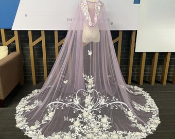 Pode incluir: Uma capa de noiva de tule lavanda com bordados florais brancos e detalhes de borboleta. A capa tem capuz e uma cauda longa.
