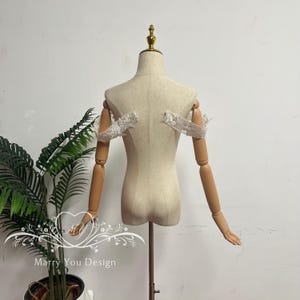 Puede incluir: Un maniqu&iacute; beige con brazos articulados de madera y un remate dorado. El maniqu&iacute; tiene una cubierta de tela y est&aacute; dise&ntilde;ado para exhibir ropa. Mangas de encaje blanco est&aacute;n adjuntas.