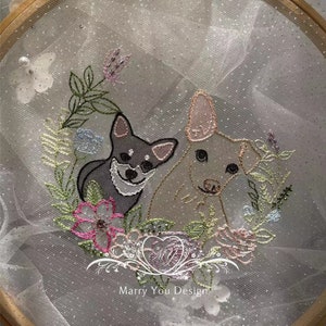 May include: Embroidered hoop art featuring two dogs, one gray and one beige, surrounded by pink, green, and white flowers. The hoop is made of wood and has a white tulle background. The text "Marry You Design" is visible at the bottom of the hoop.