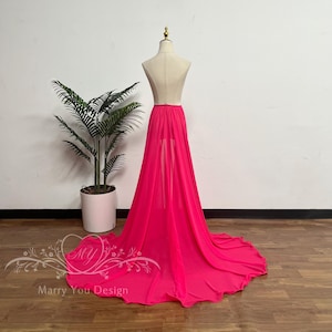 May include: A vibrant fuchsia skirt with a long train is displayed on a mannequin. The skirt is made of a flowing, sheer fabric. The mannequin is set against a white wall and a wooden floor. The text "Marry You Design" is visible.