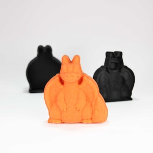 May include: Orange dragon-shaped cookie cutter with two black bat-shaped cookie cutters in the background.