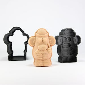 May include: A brown plastic mold of a cartoon potato character with a hat, arms, and legs. The mold is next to a black plastic mold of the same character.
