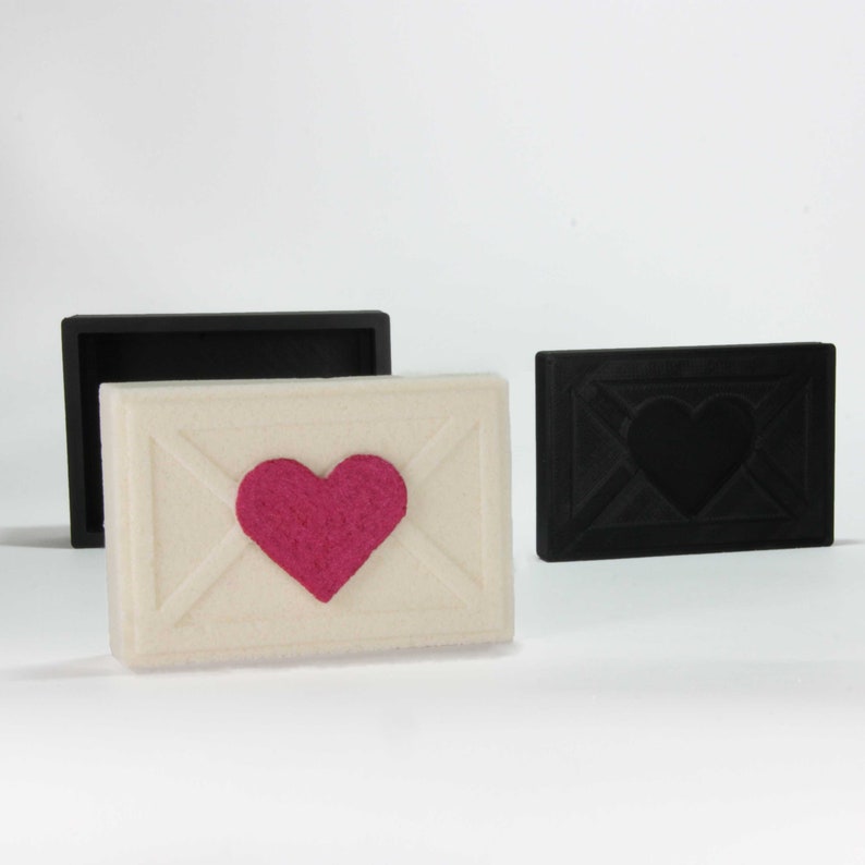 May include: Three decorative boxes, one white with a pink heart, one black with a black heart, and one black with a blank interior.