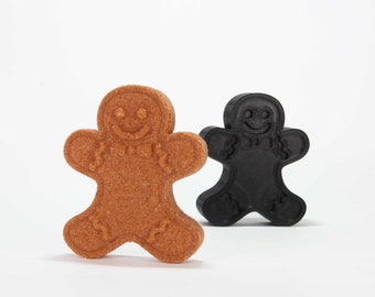 Puede incluir: Dos galletas de hombre de jengibre, una marrón y otra negra. El hombre de jengibre marrón está de pie, mientras que el hombre de jengibre negro está tumbado.