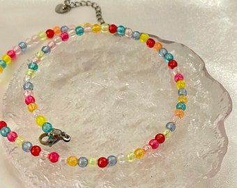 May include: A colourful beaded necklace with a silver clasp. The beads are in shades of red, orange, yellow, green, blue, and purple.