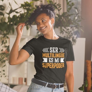 May include: A black t-shirt with white text that reads "Ser multilingüe es mi superpoder". The text is in a distressed font and is surrounded by arrows.