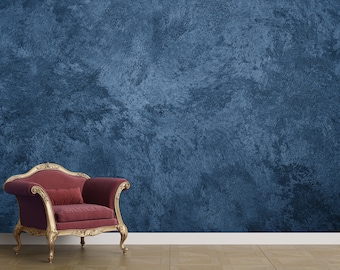 Könnte beinhalten: Ein Sessel im Vintage-Stil mit rotem Samtbezug und vergoldetem Holzrahmen. Der Sessel steht vor einer blauen, strukturierten Wand.