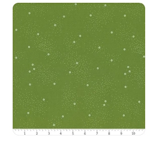 May include: Green fabric with a speckled pattern and small white circles. The fabric has a ruler along the bottom edge, marked in inches. The fabric is a solid green color.
