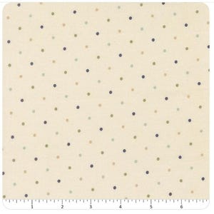 May include: A cream-colored fabric featuring a repeating pattern of small, evenly spaced polka dots in shades of navy blue, sage green, and tan. A white ruler is visible at the bottom edge, showing measurements in inches up to 6.5 inches.