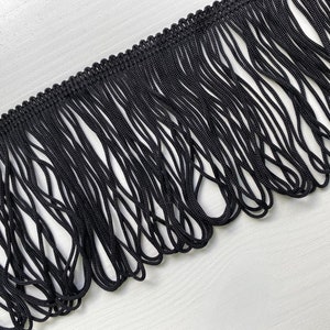Puede incluir: Borde de flecos negro con un borde tejido. Los flecos están hechos de cordones negros finos.