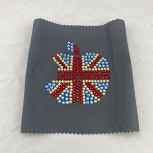 May include: A gray fabric patch with a red, white, and blue Union Jack design made of rhinestones. The design is in the shape of an apple.
