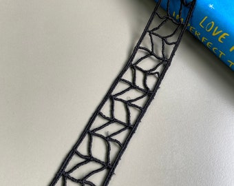 May include: Black lace trim with a geometric pattern. The trim is about 1 inch wide and is made of a delicate, lightweight material.