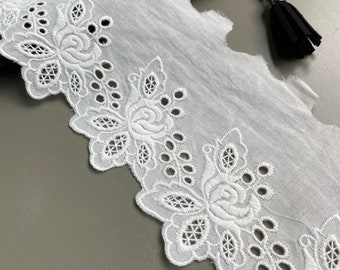 May include: White cotton lace trim with a scalloped edge and a floral design. The lace has a delicate, intricate pattern with small holes throughout.