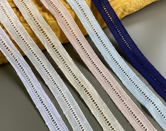 May include: Six different colors of cotton lace trim with a scalloped edge. The colors are white, light blue, light gray, beige, pink, and navy blue.