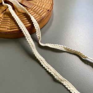 May include: A close-up of a white crocheted trim with a delicate scalloped edge.