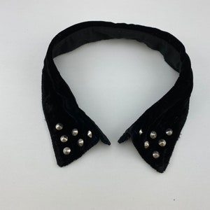 May include: A black velvet collar with silver studs. The collar is pointed and has a wide opening.