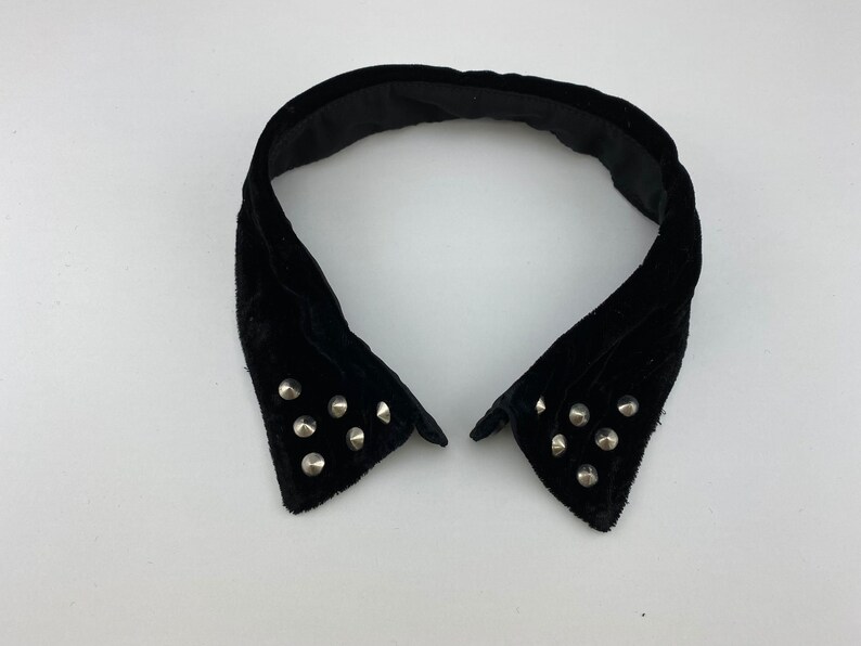 May include: A black velvet collar with silver studs. The collar is pointed and has a wide opening.