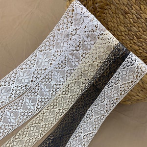 May include: Three different lace trims in white, cream, and black. The lace is delicate and intricate with a floral pattern.