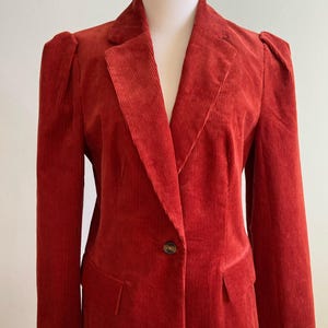 Könnte beinhalten: Ein roter Cordblazer mit einem Knopfverschluss und einem klassischen Revers.
