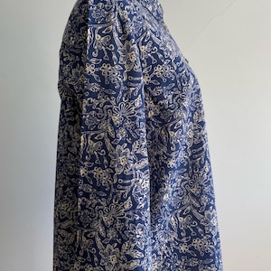 Peut inclure: Chemise bleu marine &agrave; boutons avec un motif floral cr&egrave;me. La chemise &agrave; manches longues est pr&eacute;sent&eacute;e sur un mannequin. Le tissu a un aspect doux et fluide, et le motif floral est r&eacute;p&eacute;t&eacute; sur tout le v&ecirc;tement.