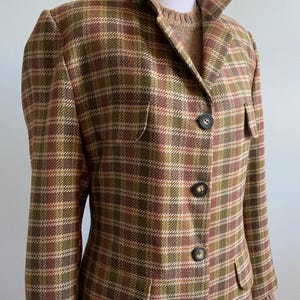 May include: A brown, green, and red plaid blazer with a collar and five buttons. The blazer has a pocket on the left side.