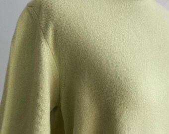 May include: A light green short-sleeve sweater with a crew neck. The sweater is made of a soft, knit material. The color is a pale, spring-like green.