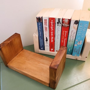 May include: A wooden bookshelf with a natural finish, holding several books with colourful spines. The books are titled "The Weight of Silence", "Bridget Jones", "A Good Girl's Guide to Murder", "Keeper of the Light", "The Queen of New Beginnings", and "Anybody Out There".