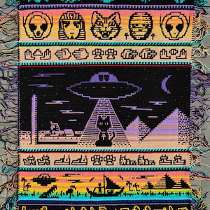 May include: A colorful, crocheted wall hanging featuring Egyptian and extraterrestrial themes. The design includes pyramids, an alien abduction scene, and hieroglyphs. The color palette includes black, purple, yellow, and blue, with fringe along the edges.