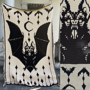 May include: A cream-colored crochet blanket with a large black bat design in the center. The blanket features a repeating pattern of bats, arrows, and a crescent moon. The edges are finished with a fringe.