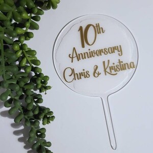 Peut inclure: Un topper de g&acirc;teau en acrylique transparent avec une inscription dor&eacute;e qui dit "10th Anniversary Chris & Kristina".