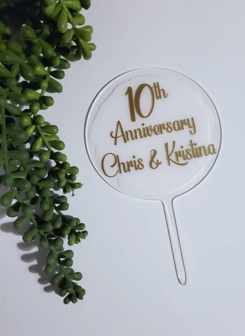 Peut inclure: Un topper de g&acirc;teau en acrylique transparent avec une inscription dor&eacute;e qui dit "10th Anniversary Chris & Kristina".